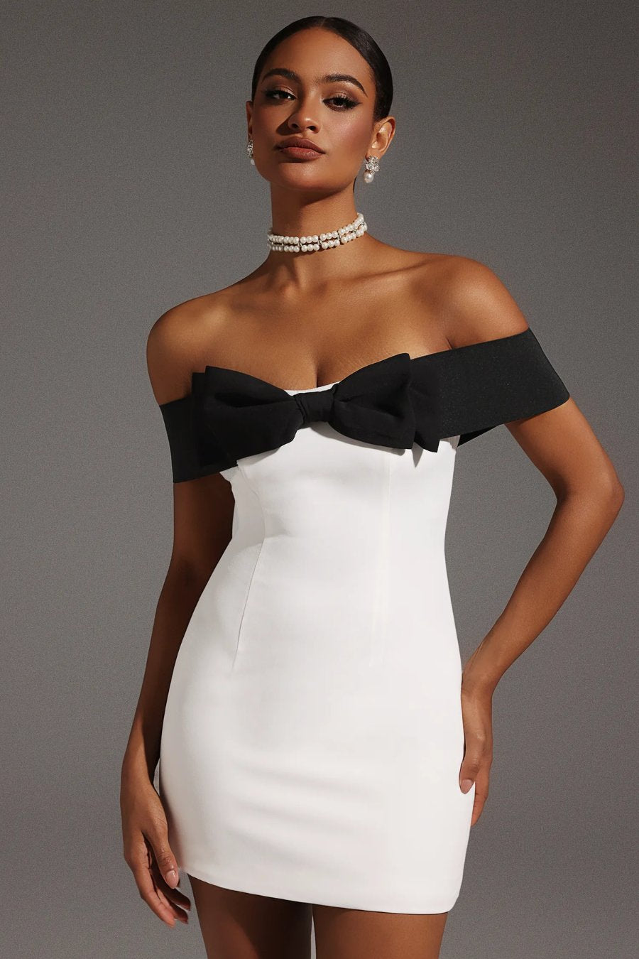 Robe blanche courte élégante avec nœud noir satiné, idéale pour soirée chic